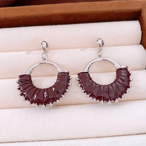 Detailed shot of silver-tone hoop earrings with deep red leather and tiny bead accents