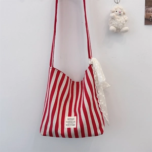 Detail of red and white striped canvas bag with lace scarf and decorative sheep charm