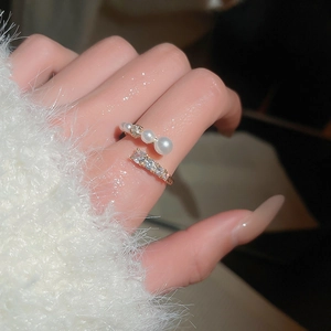 Detail of adjustable gold-plated ring with pearls and cubic zirconia on a model hand