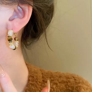 Detailed view of vintage gold hoop earrings with brown tiger eye and cream beads on ear
