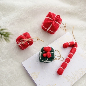 Handmade wool felt Christmas tree ornaments with candy canes and gift boxes on festive card