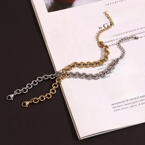 Polished 14K gold and silver chunky chain bracelets displayed on a minimalist magazine