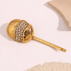 Macro detail of gold eggshell hair clip with sparkling rhinestones and water droplet texture