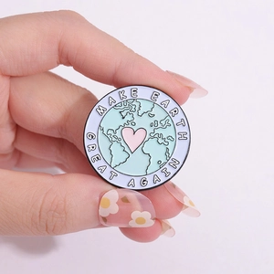 Pin's rond en émail avec terre bleue et cœur rose portant le texte Make Earth Great Again