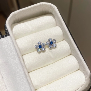 Makroaufnahme von Silber-Blumenohrsteckern mit blauem Stein und weißen Zirkonia-Kristallen