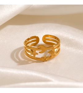 Detailed close-up of triple-layered gold star and moon ring on white silk fabric