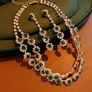 Luxuriöses Schmuckset mit Goldkette und Ohrringen mit grünen Steinen und Blumen