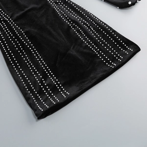 Détail de la robe en velours noir avec des motifs linéaires de perles décoratives blanches