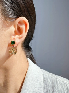Détail macro d'une pierre vert émeraude et boucle d'oreille dorée en relief de cheval