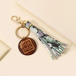 Detail of wooden MAMA charm with floral engraving and colorful camouflage tassel keychain