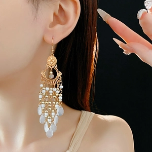 Detailed view of long ethnic tassel earrings with gold-toned metal and white beads