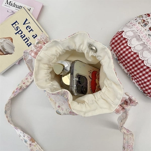 Detailed view of cream floral canvas crossbody bag with lace trim and magnetic closure