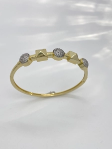Detailed top view of gold bangle featuring pavé-set crystal spheres and pyramid studs