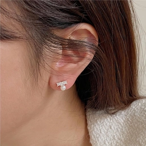Detailed view of elegant pearl stud earrings with zircon stones worn on an ear