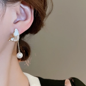Elegant gold butterfly earrings with zircon accents and pearl drops on a model