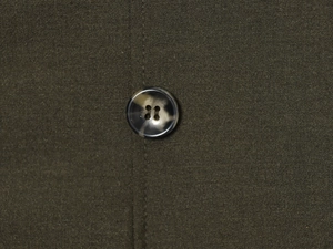 Detailed macro view of olive green fabric texture with a marble pattern button detail