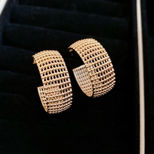 Macro shot of gold mesh texture C-shaped earrings inside a black velvet jewelry box