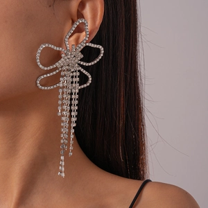 Detailed close-up of a silver bow earring with shimmering rhinestone tassel chains