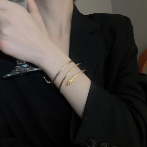 Detailed view of golden snake wrap bracelet with scale texture on a model's wrist