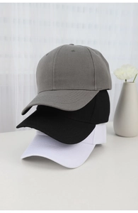 Detailed stack of cotton baseball caps in grey, black, and white on a clean white desk