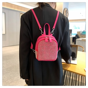 Detail of bright pink backpack with silver rhinestone studs against black blazer background