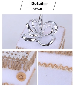 Detail of white felt wedding ring box with silver petals, jute tassels and lace trim