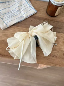 Detail of elegant beige lace bow hair claw clip with embroidery and hanging bead