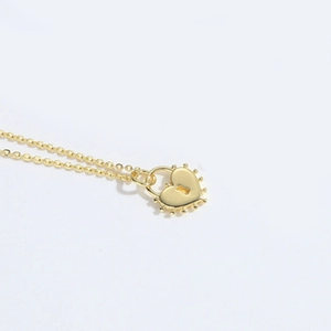 Close-up of golden heart lock pendant with beaded edge and fine chain details