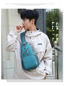 Detail of teal crossbody bag showing multiple zipper pockets and wide shoulder strap
