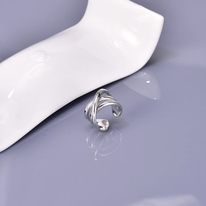 Macro shot of polished silver multilayer winding cross ring in minimalist design