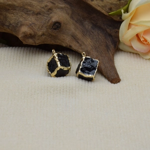 Detailed macro view of black resin cube charms with vintage gold-plated irregular frames