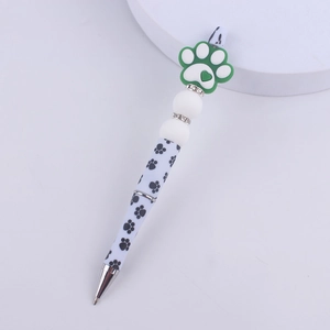 Detail of beaded pen featuring green silicone paw charm and black paw prints on white barrel