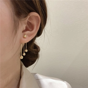 Detailed view of elegant gold long tassel earrings with bead drops worn by a model