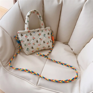 Detailed close-up of a quilted floral mini bag with a colorful braided shoulder strap