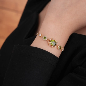 Détail macro du bracelet plaqué or avec cristaux de zircon vert sur un poignet