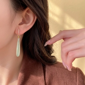 Elegant water drop earrings with light green pendant and white rhinestones on model