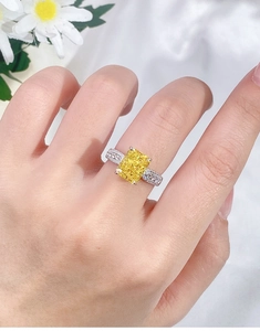 Close-up of a s925 silver ring with a square yellow diamond on a hand with white daisies