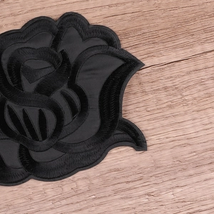 Black rose floral embroidery patch on a wooden background for DIY clothing decoration