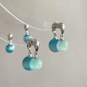 Close-up of hoop earrings with dual blue and mint green translucent resin beads