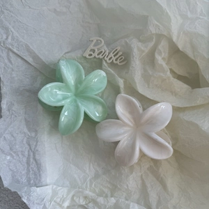 Floral plastic hair claws in creamy green and off-white with smooth marble texture
