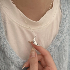 Minimalist 925 sterling silver croissant moon necklace on model with knit cardigan