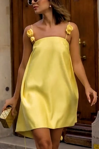 Detail of yellow satin slip dress featuring elegant 3D floral strap and smooth fabric texture