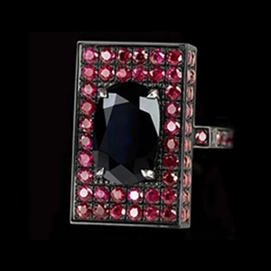Macro shot of square blue sapphire ring with red gemstone halo and black metal plating