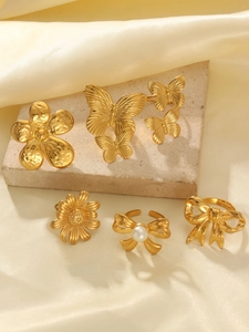 Detailed view of gold plated butterfly rings and jewelry on soft beige fabric