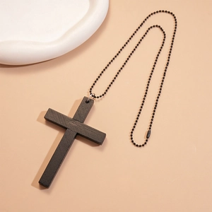 Collier gothique avec pendentif croix en bois noir et chaîne à perles sur fond épuré