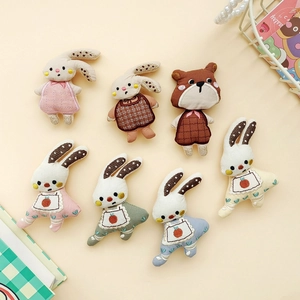 Detailed view of seven assorted fabric bunny and bear doll brooches for DIY crafts