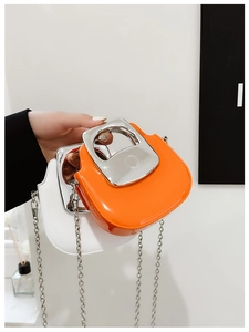 Detail of mini bags in orange and white with U-shaped silver metal handles and chains