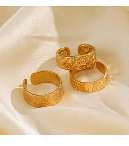 Detailed view of three vintage-style wide gold stainless steel rings on silk fabric