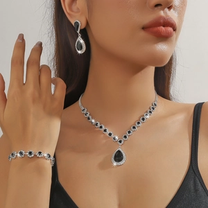 Close-up of model wearing silver necklace, earrings and bracelet set with black gems