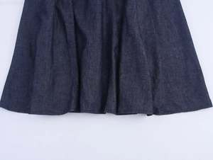 Gros plan détaillé de l'ourlet de la robe en jean bleu foncé avec plis et coutures
